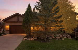 View of front facade with stone siding, driveway, and a yard
