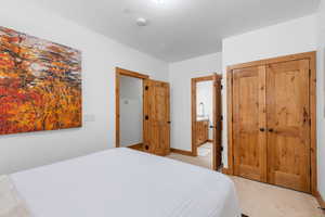 Bedroom featuring light carpet, a closet, and ensuite bathroom