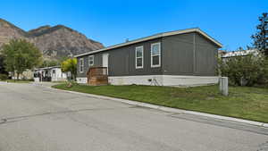 View of property exterior with a yard and a mountain view