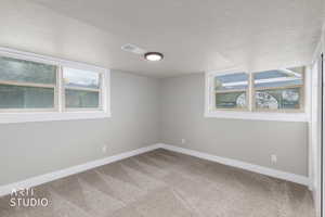 Carpeted empty room with baseboards and a textured ceiling
