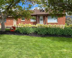 Ranch-style home with a front lawn, brick siding, and a chimney