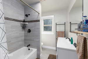 Full bath with shower / bath combination, vanity, and light wood finished floors