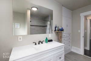 Full bathroom with vanity, wood tiled floors, and tiled shower
