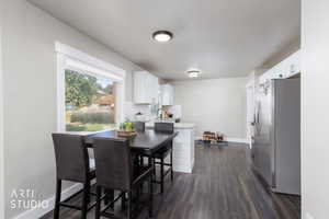 Dining space with dark wood-style flooring and baseboards