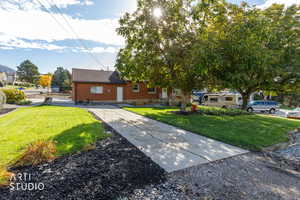 View of front of home with brick siding, a front lawn, and roof with shingles