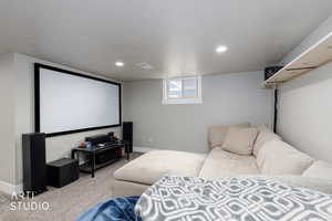 Cinema room featuring carpet, recessed lighting, and a textured ceiling