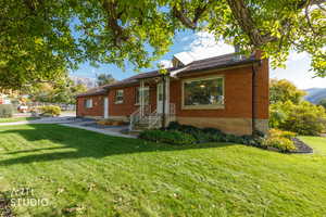 View of front of property with brick siding, a front lawn, a mountain view, and a chimney
