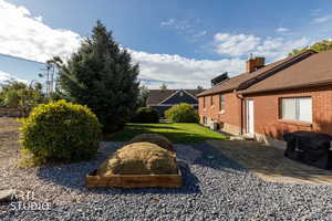 View of green lawn with a vegetable garden and a patio area