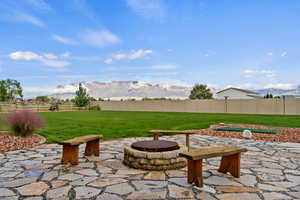 Fenced backyard featuring a mountain view, a patio area, and an outdoor fire pit