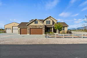 Craftsman-style house featuring concrete driveway, a fenced front yard, stone siding, stucco siding, and a mountain view