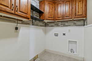 Washroom featuring light tile patterned floors, cabinet space, electric dryer hookup, and hookup for a washing machine
