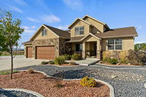 Craftsman-style home featuring stucco siding, stone siding, concrete driveway, and a shingled roof