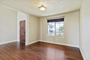 Empty room with a textured ceiling and dark wood-style floors