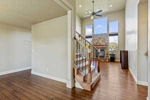 Stairway with a fireplace, hardwood / wood-style floors, a textured ceiling, a ceiling fan, and recessed lighting