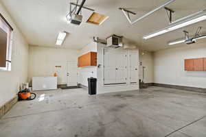 Garage featuring a heating unit, a garage door opener, and white fridge