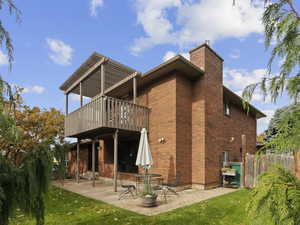 Rear view of house with a patio area, a chimney, and brick siding
