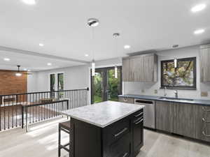 Kitchen with light wood finished floors, pendant lighting, a center island, dishwasher, and recessed lighting