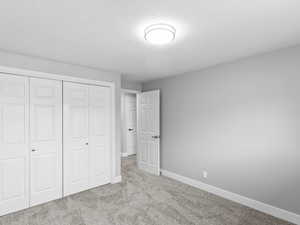 Unfurnished bedroom with carpet floors, a textured ceiling, and a closet