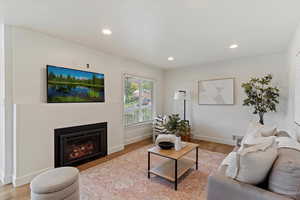 Living room with light wood-style floors, recessed lighting, and a glass covered fireplace
