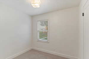 Spare room featuring carpet and a textured ceiling