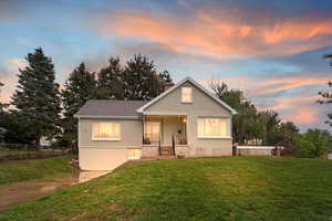 Bungalow with a front lawn, a chimney, brick siding, and covered porch