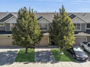 View of front of property featuring board and batten siding, roof with shingles, concrete driveway, an attached garage, and brick siding