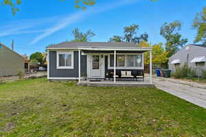 Back of property featuring a sunroom, a patio, and a shingled roof