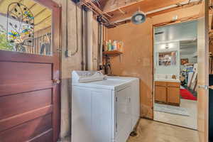 Rear basement entrance to left. Laundry area featuring unfinished concrete flooring and independent washer and dryer