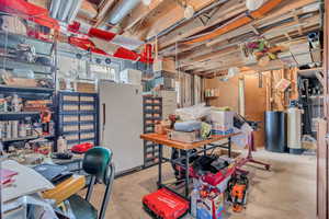Basement featuring a water softener system and freestanding refrigerator