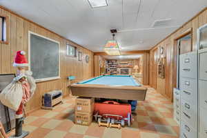 Game room featuring wood walls, light floors, a large fireplace, and pool table