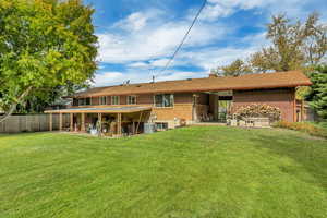 Back of house with a patio, a chimney, brick siding, and a shingled roof