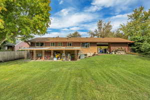 Rear view of property with a patio area, a yard, and brick siding