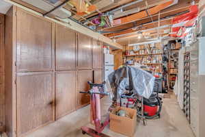 Basement with freestanding refrigerator and a workshop area