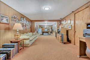 Carpeted living room with wooden walls and pool table