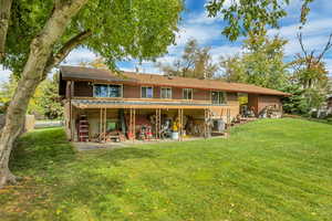 Back of house featuring a patio area, a yard, and brick siding