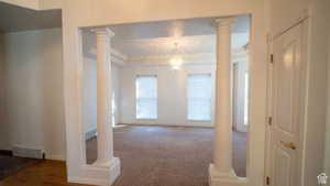 Empty room featuring a chandelier, ornate columns, and a tray ceiling