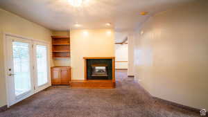 Unfurnished living room featuring a fireplace and dark carpet