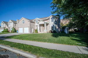 View of front of home featuring a front yard, concrete driveway, an attached garage, and brick siding