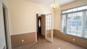 Unfurnished dining area with carpet floors and a chandelier