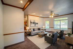 Carpeted living room featuring ceiling fan and ornamental molding