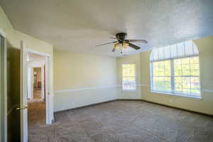 Carpeted spare room with a textured ceiling and a ceiling fan