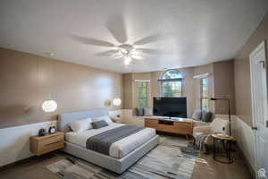 Carpeted bedroom featuring a textured ceiling and a ceiling fan