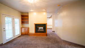 Unfurnished living room featuring a tile fireplace, carpet flooring, and a textured ceiling