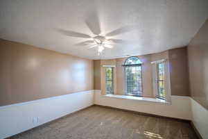 Carpeted spare room featuring a textured ceiling and a ceiling fan