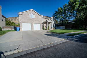 View of front of house with driveway, a garage, and brick siding