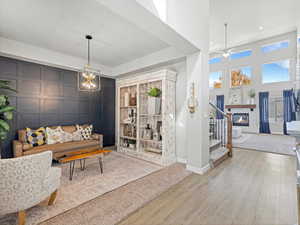 Living room with a tiled fireplace, a high ceiling, wood finished floors, recessed lighting, and a ceiling fan