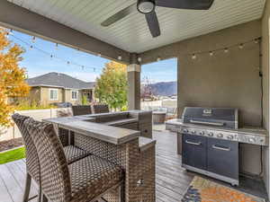 Deck featuring grilling area, a mountain view, a ceiling fan, and an outdoor living space