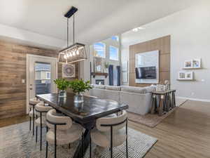 Dining room with wood walls, a tiled fireplace, and wood finished floors