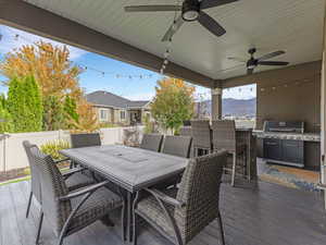 Deck featuring outdoor dining area, a mountain view, a fenced backyard, a ceiling fan, and area for grilling
