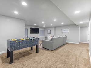 Recreation room with light colored carpet and recessed lighting